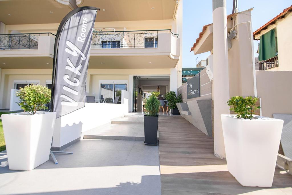 a walkway outside of a building with potted plants at Vicky Rooms in Paralia Dionysiou