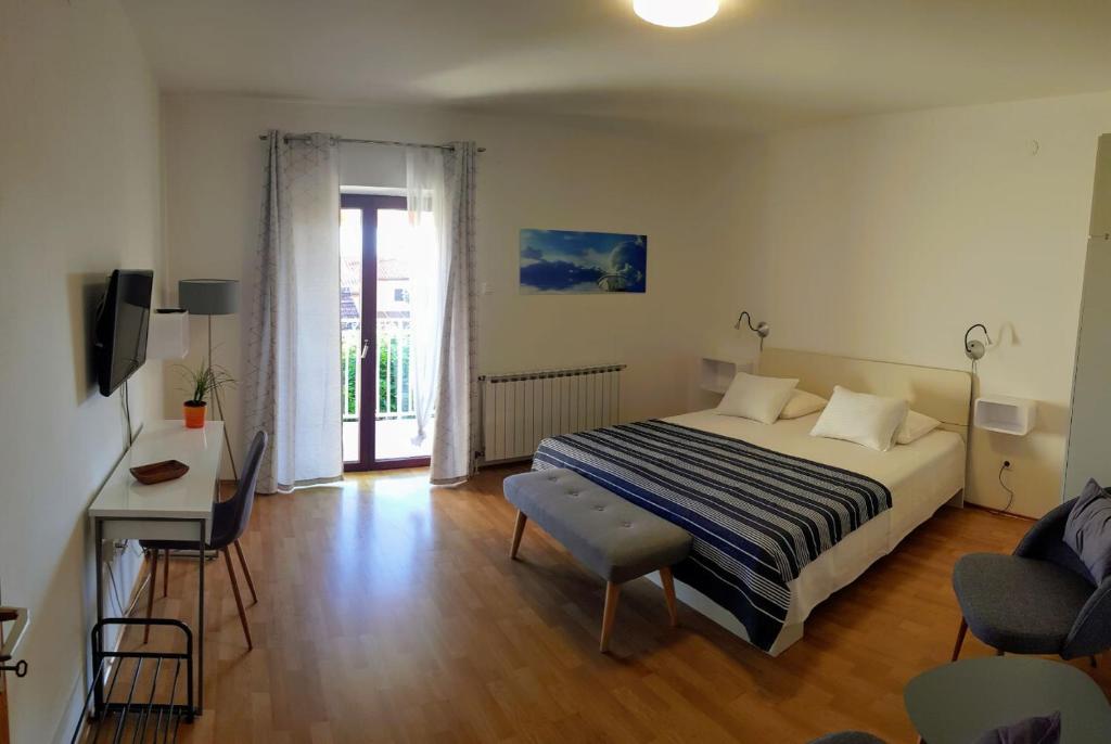 a bedroom with a bed and a desk and a tv at Apartments & Rooms Tom in Medulin