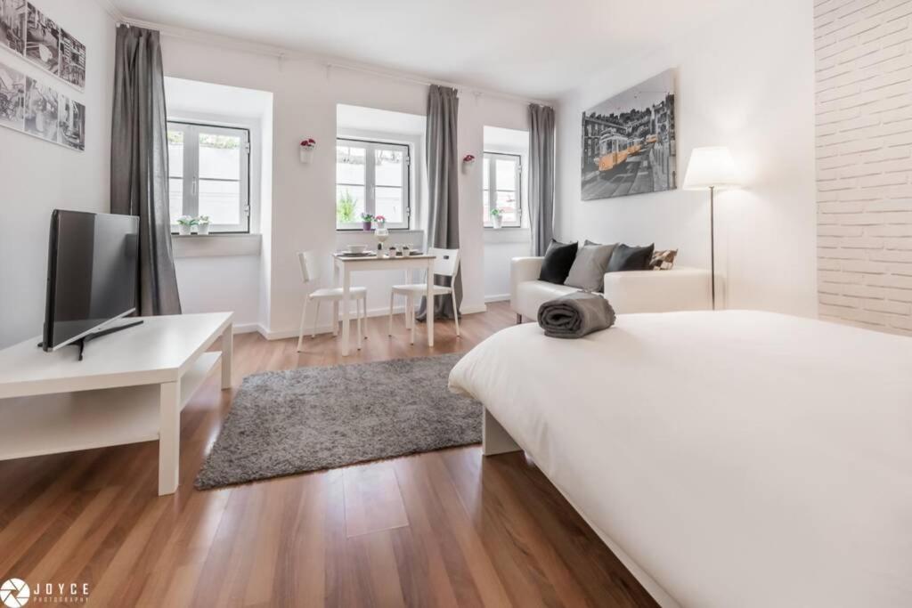 a white bedroom with a bed and a desk with a television at InLoveApartments - Under A Fig Tree in Lisbon