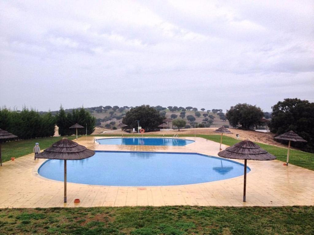 a large swimming pool with umbrellas in a field at O Cantinho Alentejano in Cuba