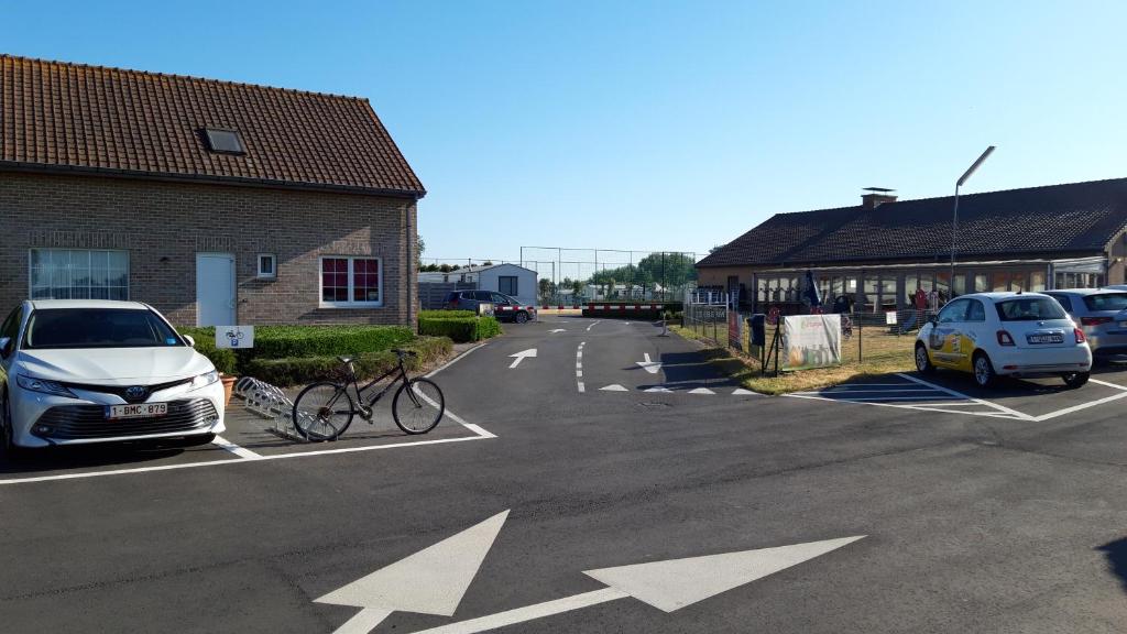 ein Fahrrad auf einem Parkplatz neben einem Gebäude geparkt in der Unterkunft Chalet Park Zeeberm CommV in Oostduinkerke