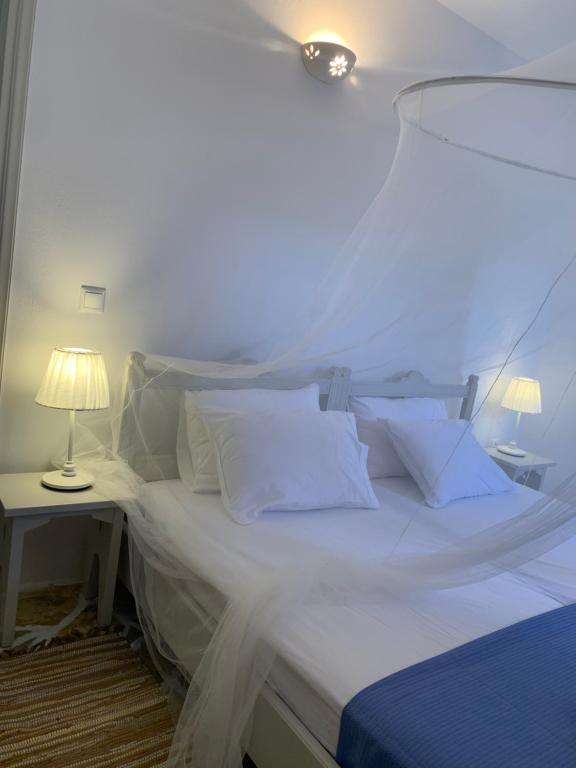 uma cama com lençóis brancos e almofadas num quarto em Keramoto Cottage - Kythoikies holiday houses em Kýthira