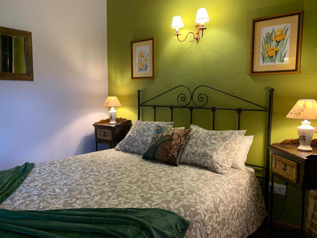 a bedroom with a bed with green walls and two lamps at El Mirador del Gato I y II in Mesegar de Corneja