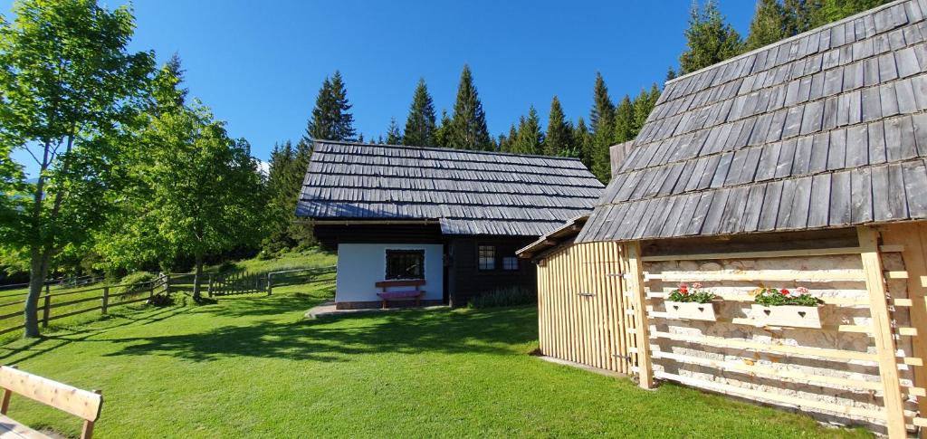 ein kleines Gebäude mit einem Zaun neben einem Hof in der Unterkunft Holiday house Žvan na Pokljuki in Bohinj