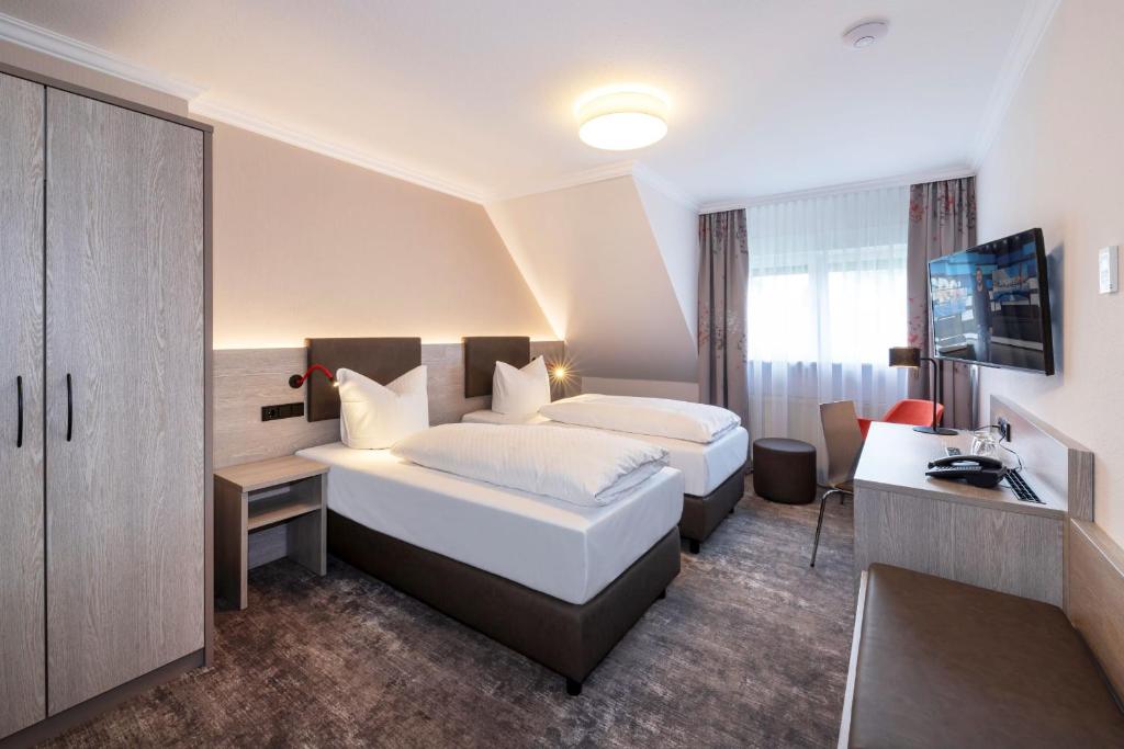 NidderauにあるHotel Alte Bäckereiのベッド2台とデスクが備わるホテルルームです。