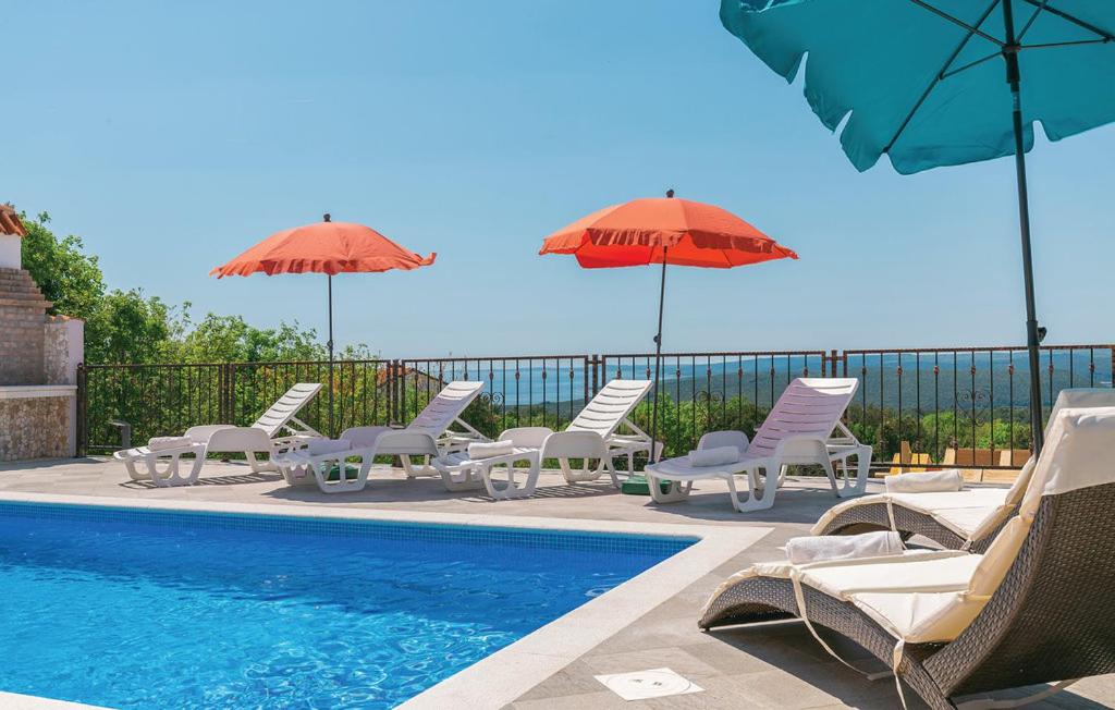 a group of chairs and umbrellas next to a pool at villa dijana in Viskovići