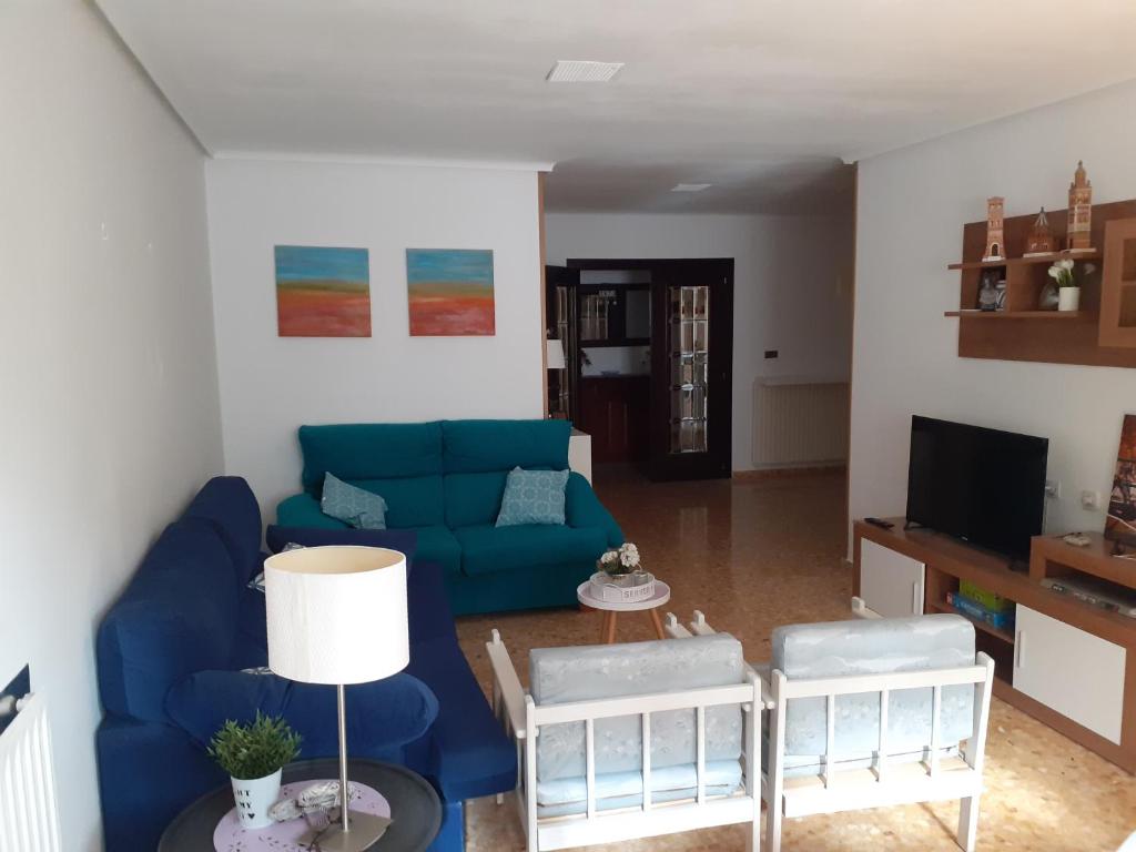 sala de estar con sofá azul y sillas en Apartamento Nuit, en Teruel