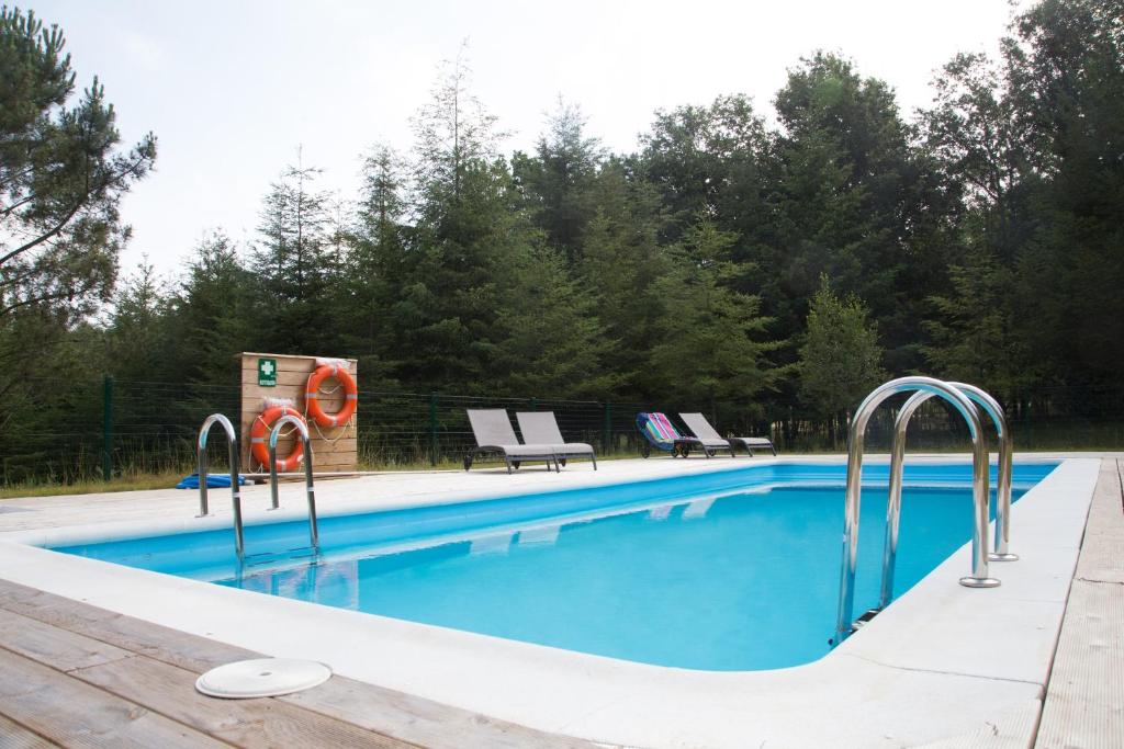 Touro的住宿－Cabanas da Ulla，一个带蓝色水和两把椅子的游泳池