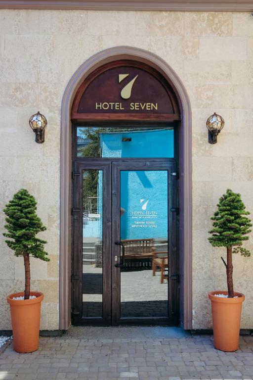 a door to a hotel with two trees in front of it at 7 Boutique Hotel in Ustʼ-Kamenogorsk