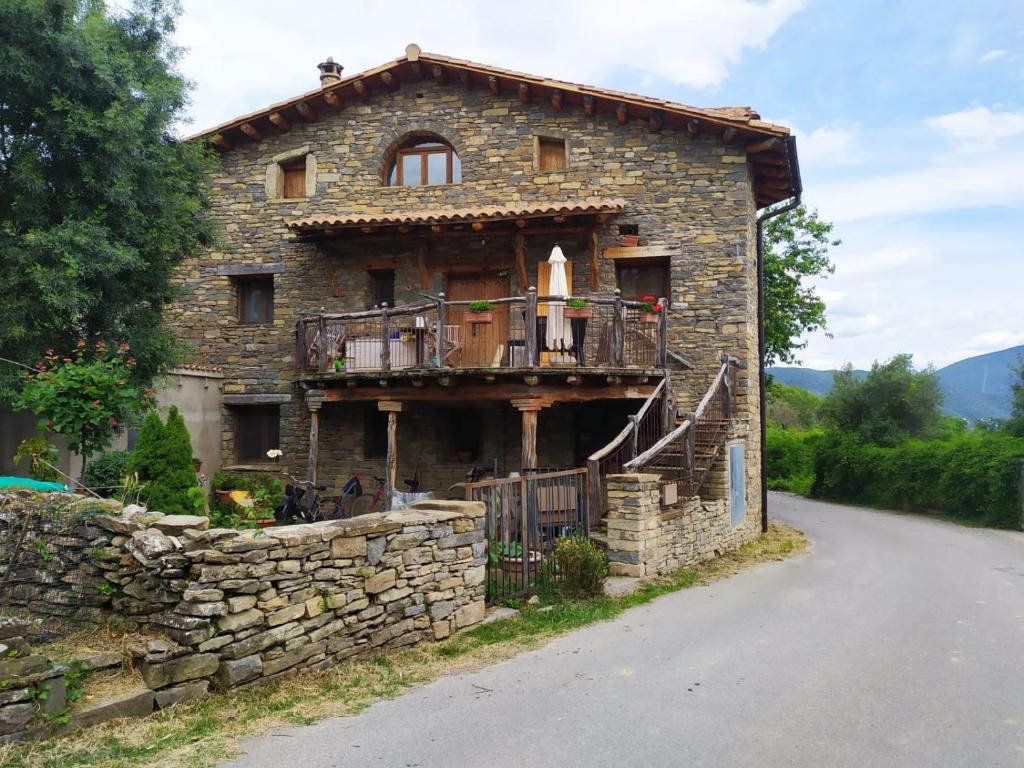 Casa de piedra antigua con balcón en la carretera en Apartamentos Borda Falceto, en Coscojuela de Sobrarbe