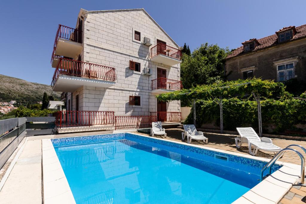 a house with a swimming pool in front of a building at Villa Valjalo in Dubrovnik