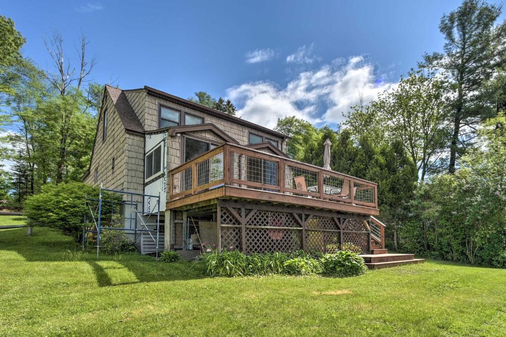 a large house with a deck on a lawn at Picturesque Cottage with Sunroom on Ashmere Lake! in Hinsdale