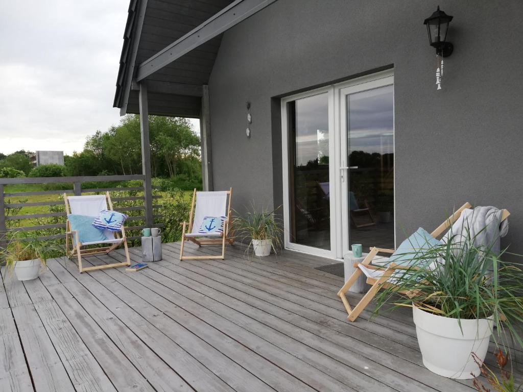 eine Terrasse mit zwei Stühlen und Topfpflanzen darauf in der Unterkunft Domek Gościnny in Darłowo