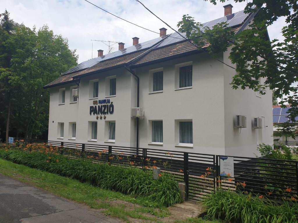 a white building with a sign on the side of it at Kid Família Panzió Balatonszárszó in Balatonszárszó
