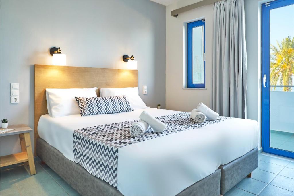 a bedroom with a large white bed and a window at Maistrali Sea View Apartments in Stalida