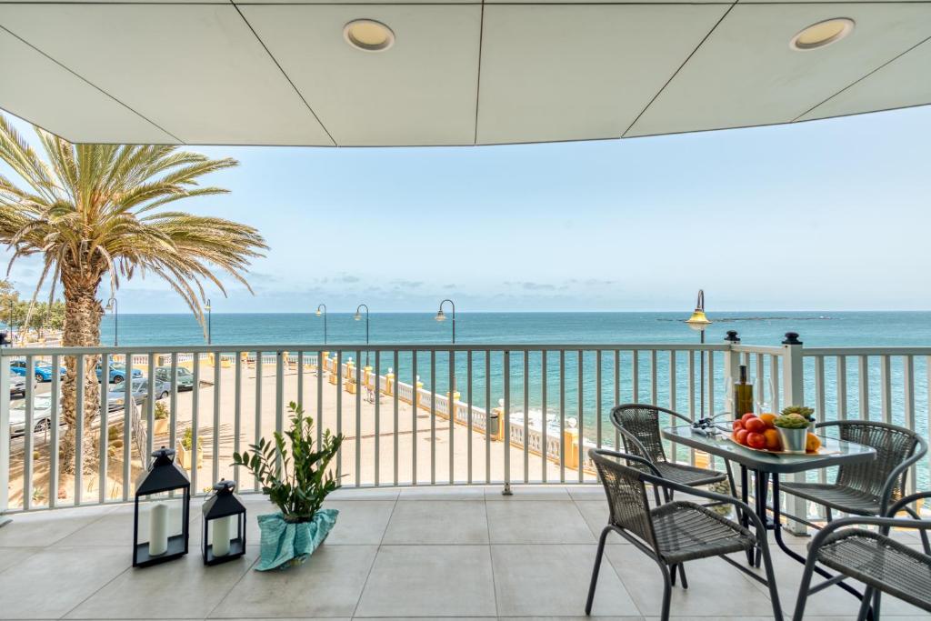 een balkon met een tafel en stoelen en de oceaan bij Durmiendo sobre el mar, El Echadero in Telde