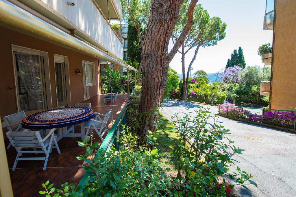 d'une terrasse avec une table, des chaises et un arbre. dans l'établissement Elegante appartamento di 200 mq con vista a Sanremo, à Sanremo