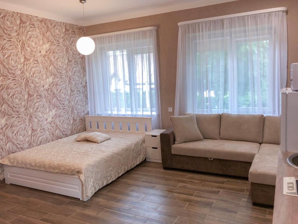 ein Schlafzimmer mit einem Bett, einem Sofa und Fenstern in der Unterkunft Marsas in Zarasai