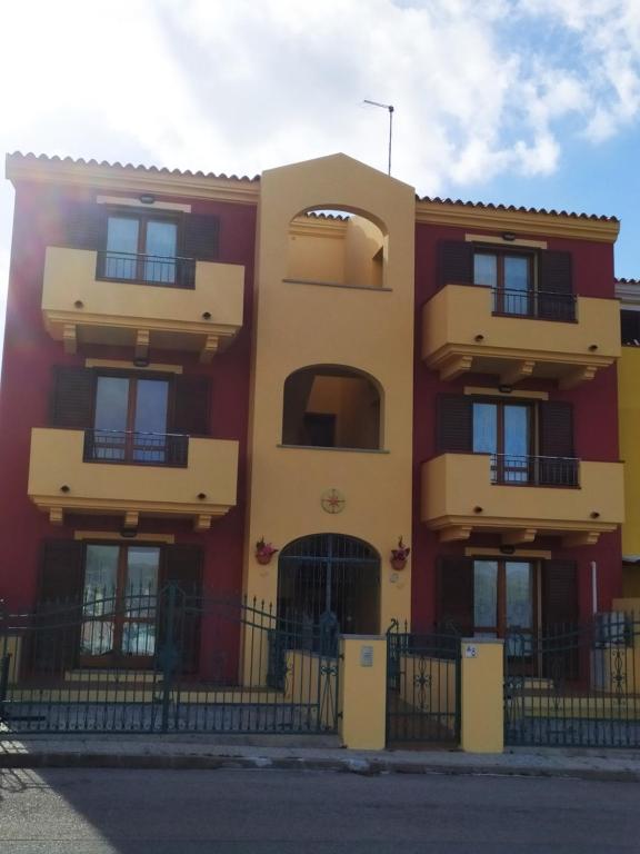 un edificio rojo y amarillo con balcones negros en L'isola incantata en Santa Teresa Gallura