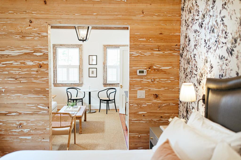 チャールストンにある86 Cannon Historic Inn - Adults Onlyの木製の壁のベッドルーム(テーブル、椅子付)