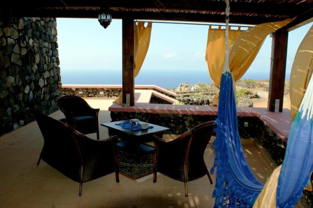 a patio with a table and chairs and a view of the ocean at Dammusi di Sofia in Pantelleria