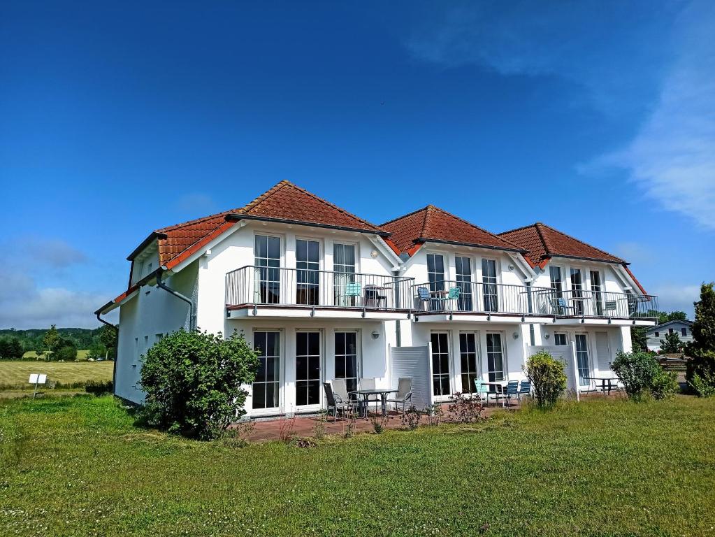 a large white house with a balcony on a field at Ferienwohnung Rügen in Sagard