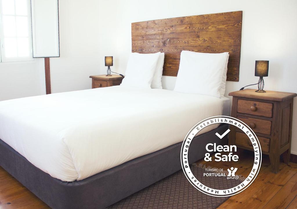 a large bed with a sign that says clean and safe at ZOETIC sustainable rooms in Évora