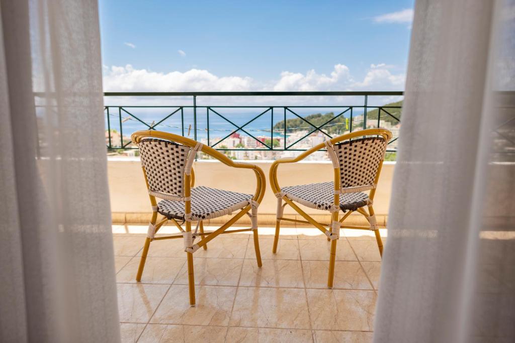 2 Stühle auf einem Balkon mit Blick auf den Strand in der Unterkunft Janakis Apartments in Himarë
