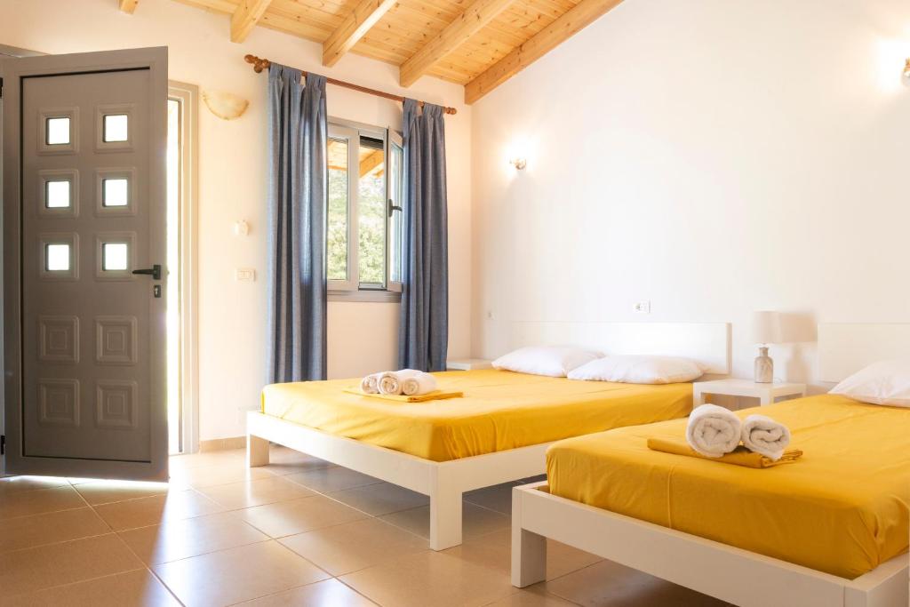 two beds in a room with yellow sheets and towels at Janakis Garden Livadi Beach in (( Spile ))