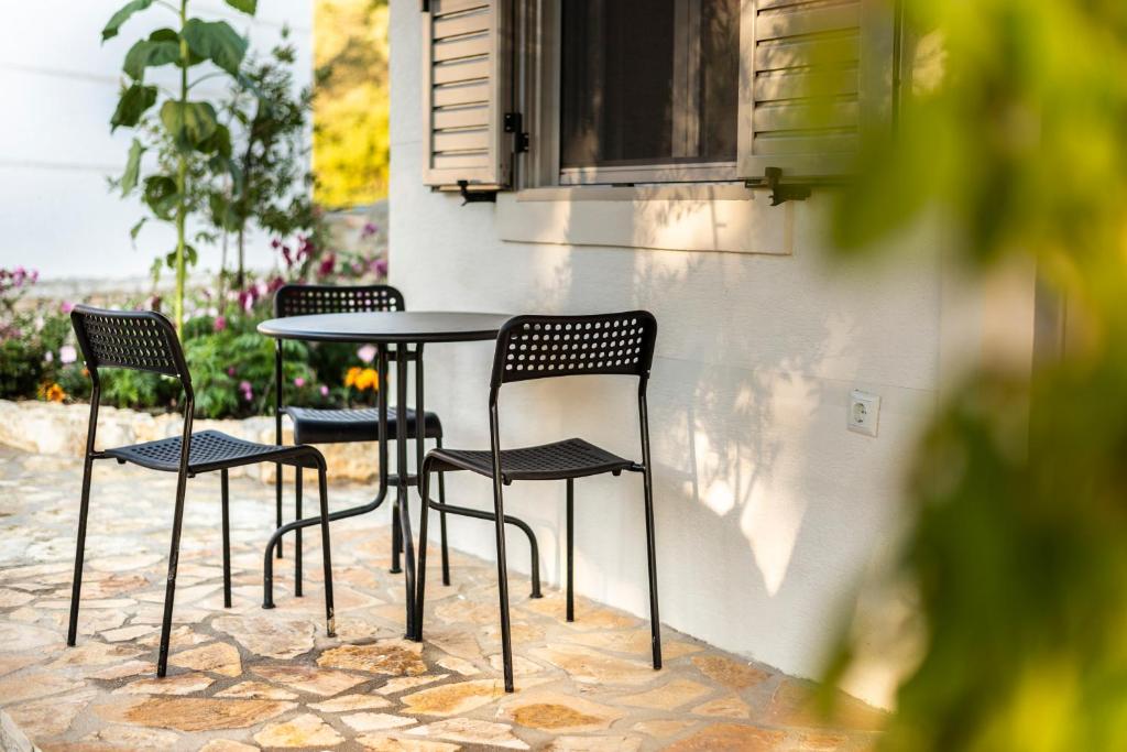 three chairs and a table in front of a building at Janakis Garden Livadi Beach in (( Spile ))