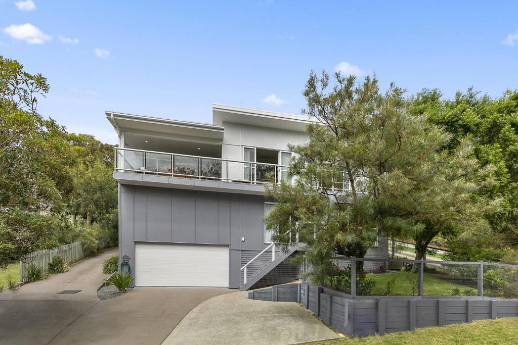 ein Haus mit einer weißen Garagentür und einem Baum in der Unterkunft Amalfi in Point Lookout