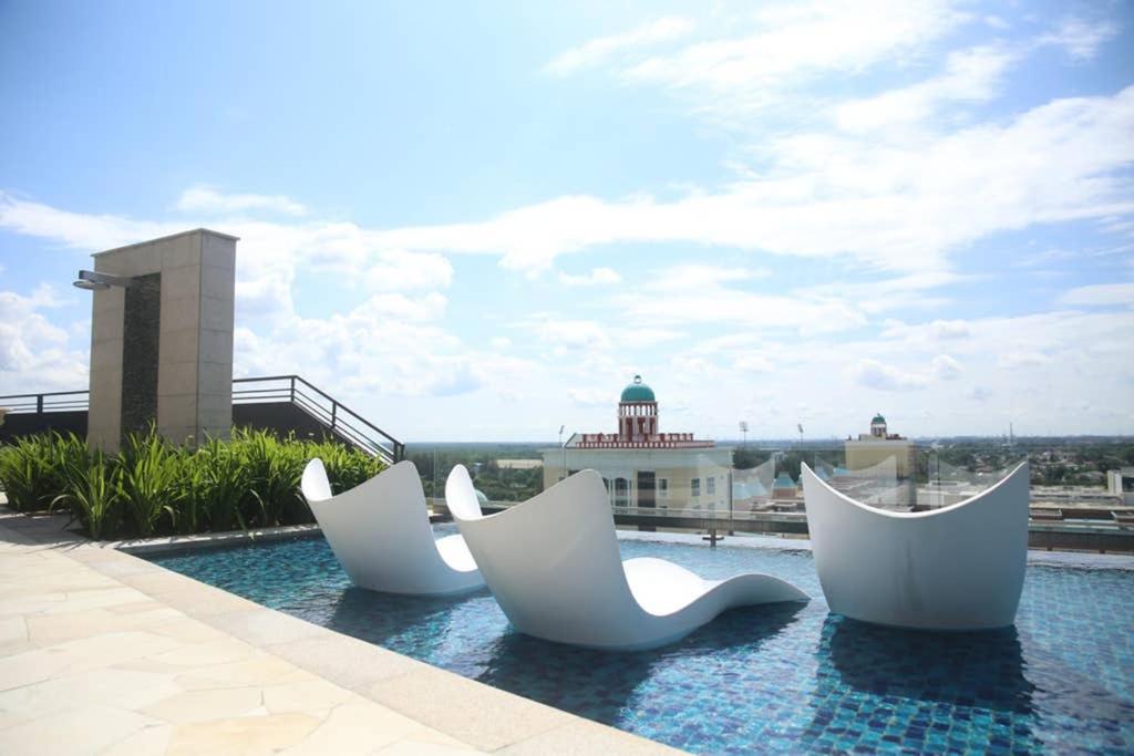 three white chairs sitting on top of a swimming pool at Enjoy Modern, Spacious, Peaceful stay with Lake view - Gravit8 in Klang