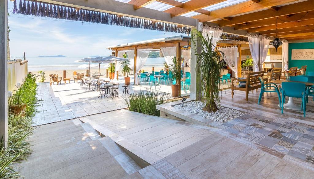 a patio with tables and chairs and the ocean at Hotel Village Enseada in Ubatuba