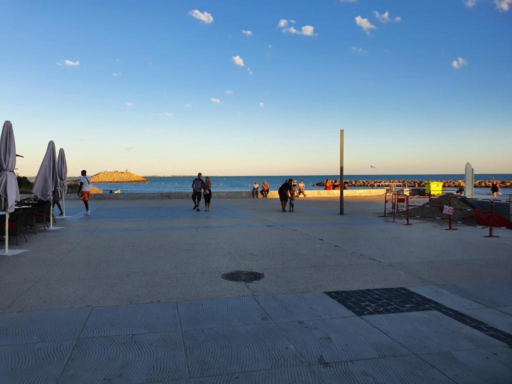 eine Gruppe von Menschen, die am Strand spazieren in der Unterkunft Grande villa indépendante proche plage et commerces grande motte in La Grande-Motte