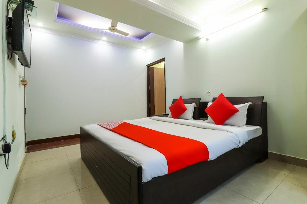 1 dormitorio con 1 cama con almohadas rojas y blancas en Hotel Sai Vatika Guest House, en Lucknow