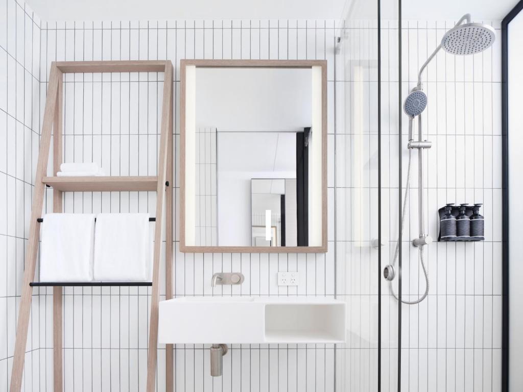a bathroom with a sink, mirror, and shower stall at Little National Hotel Sydney in Sydney