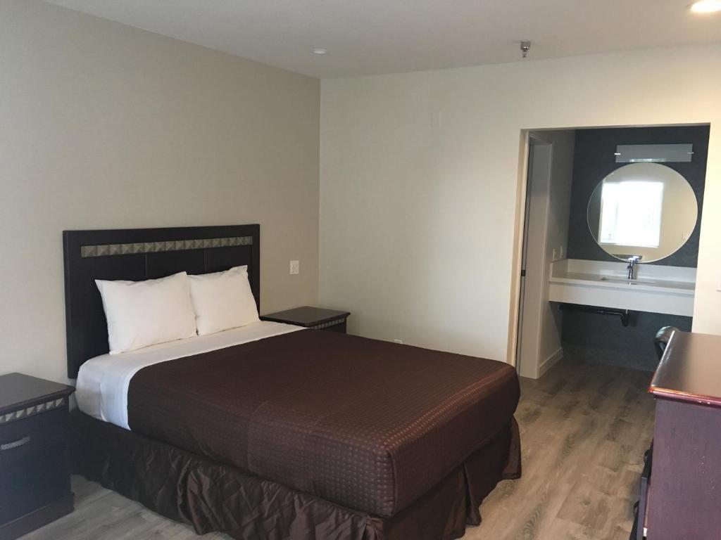 Habitación de hotel con cama y espejo en PASADENA LODGE, en Pasadena