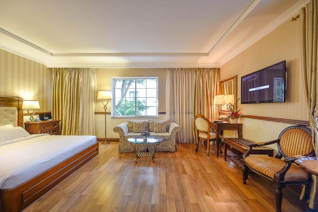 ein Hotelzimmer mit einem Bett, einem Tisch und Stühlen in der Unterkunft Boutique Garden Hotel in Ho-Chi-Minh-Stadt