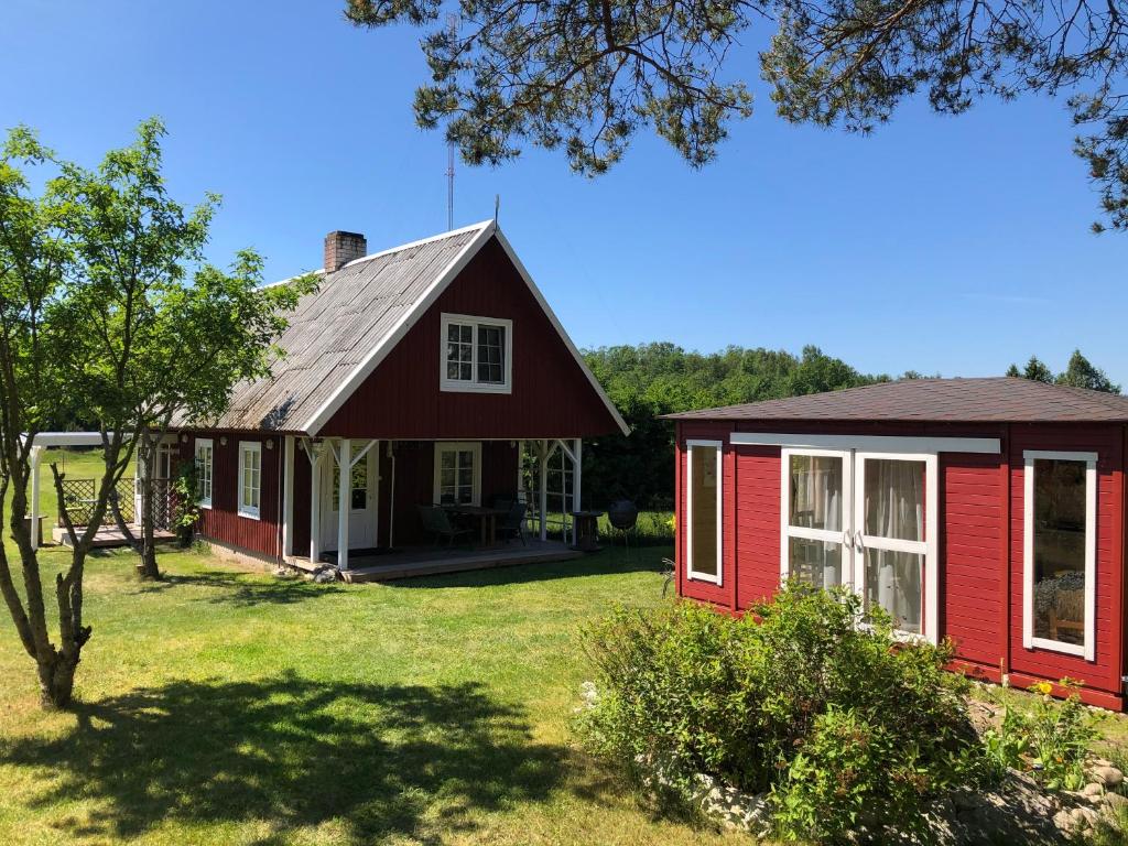 a red house with a white window and a yard at Sarapuu puhkemaja in Hullo