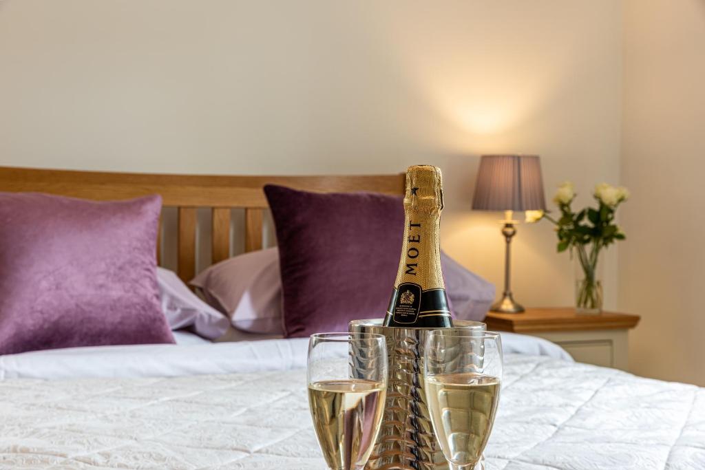 a bottle of champagne and two glasses on a bed at Slades Farm in Edington