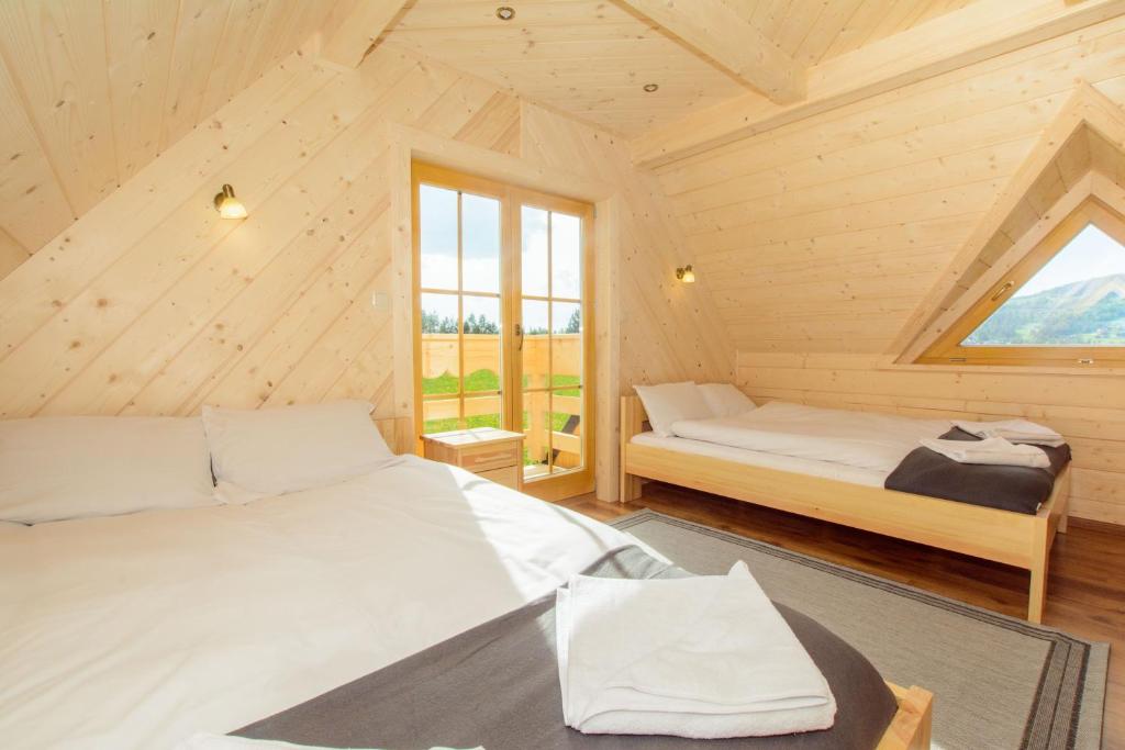 Cette chambre en bois dispose de 2 lits et d'une fenêtre. dans l'établissement Domek Trzy Doliny Zakopane, Three Valleys Chalet with Jacuzzi, à Zakopane