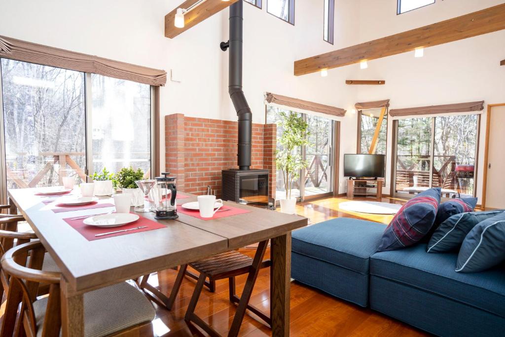 a living room with a table and a blue couch at Guest house Japan Kita-Karuizawa in Saikubo