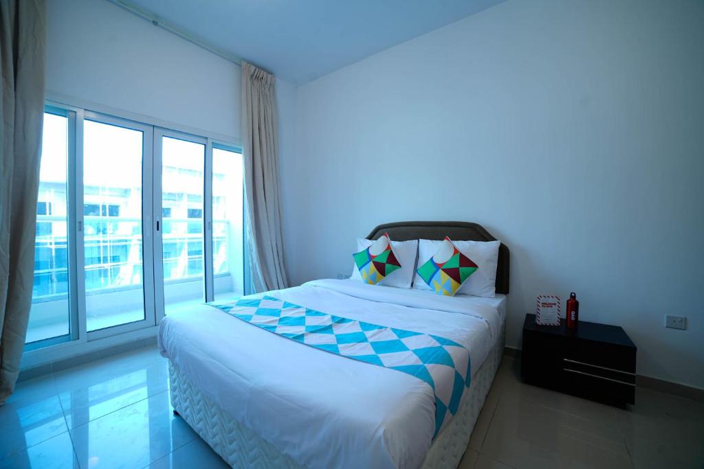 a bedroom with a bed and a large window at OYO Home 483 1BHK Tamcon DIP in Dubai