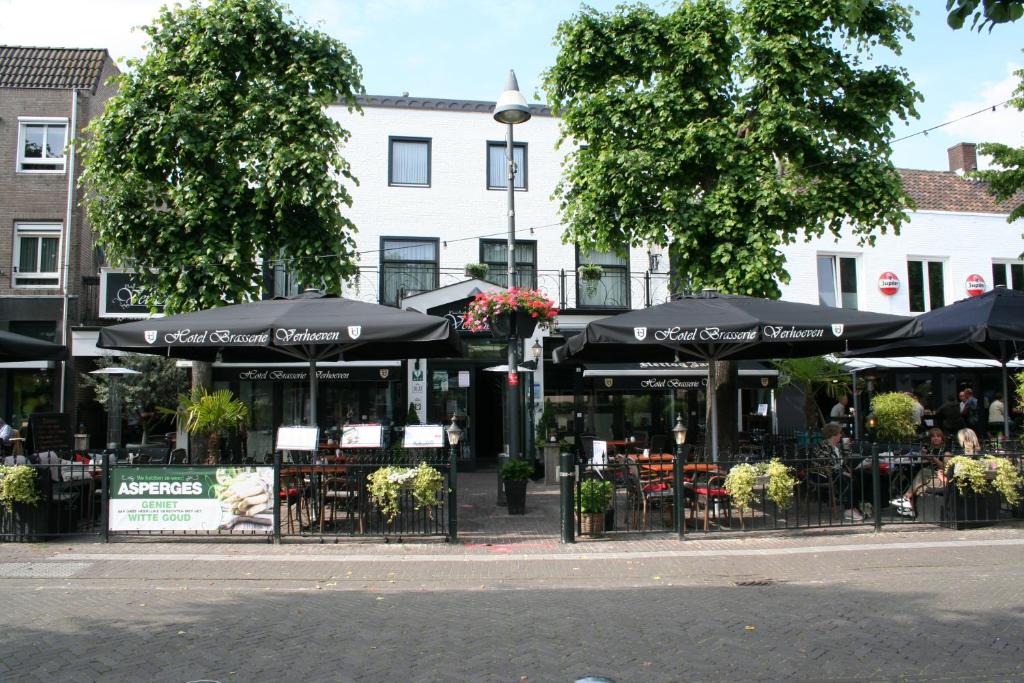 una cafetería con mesas y sombrillas en una calle de la ciudad en Hotel Verhoeven en Uden