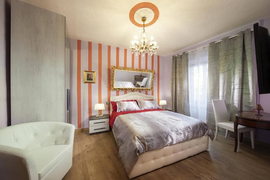 ein Schlafzimmer mit einem Bett, einem Stuhl und einem Spiegel in der Unterkunft La Togata Hotellerie de Charme - Relais il Pozzo in Montalcino