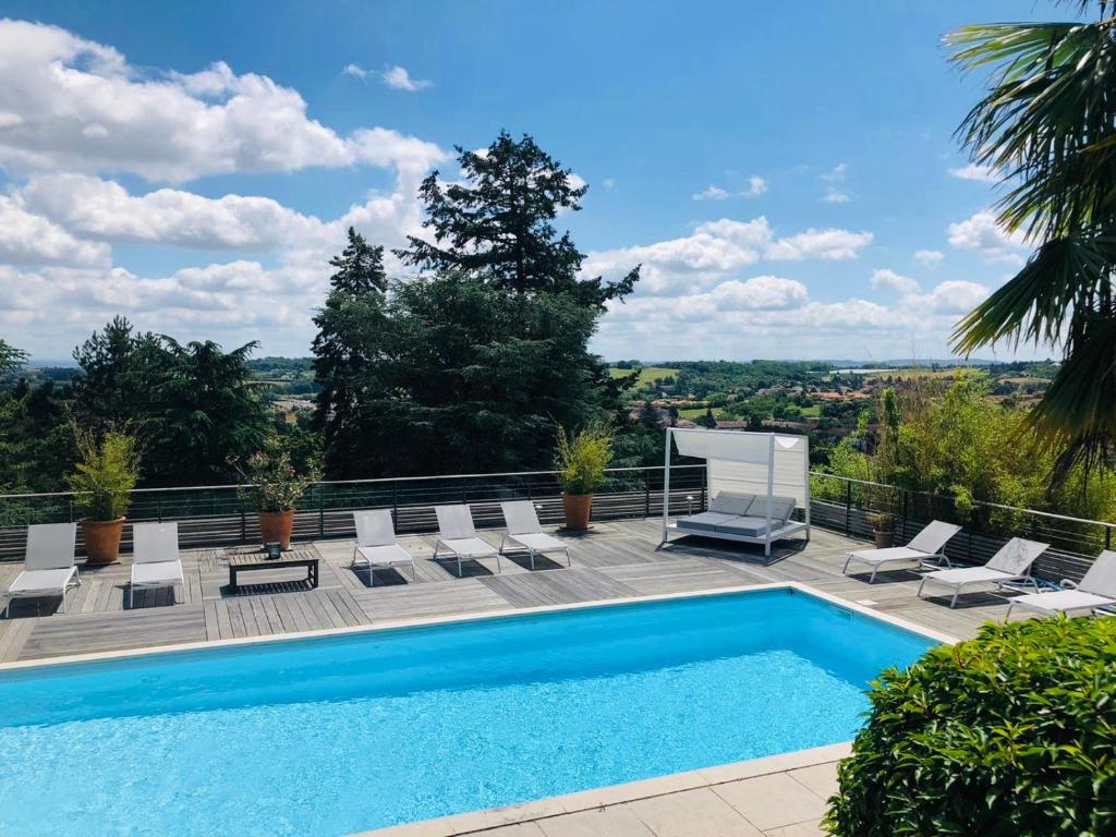 a swimming pool on a patio with lounge chairs at La Souveraine in Saint-Genis-Laval