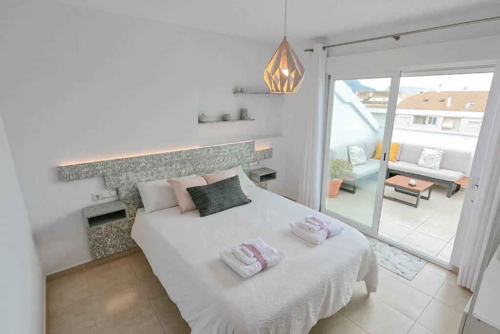 a white bedroom with a bed with two towels on it at ÁTICO ALTEA BLANCA in Altea
