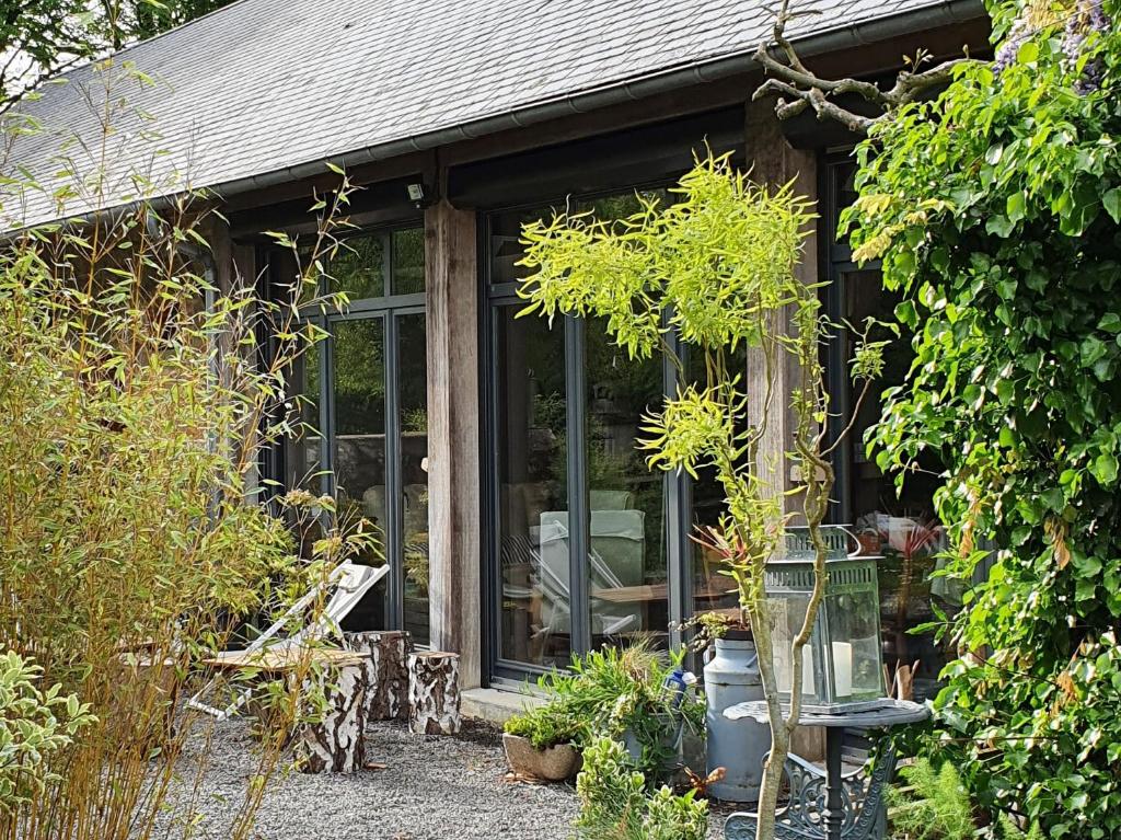 a garden room with glass doors and plants at Graine de Reves in Saint-Sauveur-la-Pommeraye