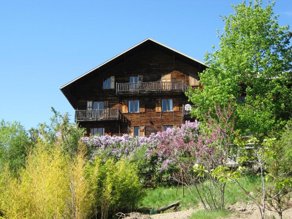 a wooden house with a balcony and some flowers at Le Vieux Chalet in Embrun