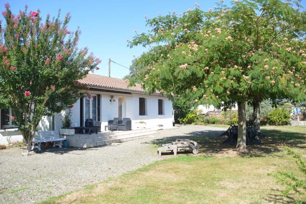 a house with two trees and a bench in the yard at VILLA AUX PIEDS DES PYRENEES in Azereix